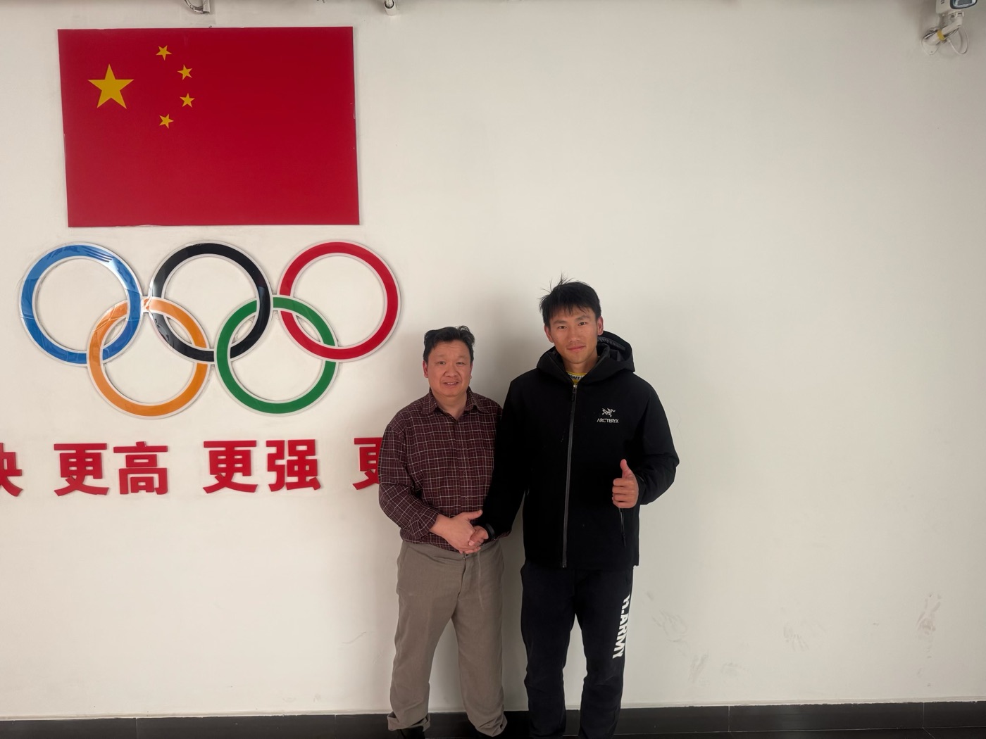 Le Dr. Long Wah avec un athlète de la délégation chinoise devant les anneaux olympiques